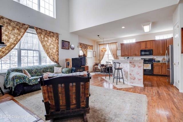 living area with a towering ceiling and light wood-style flooring