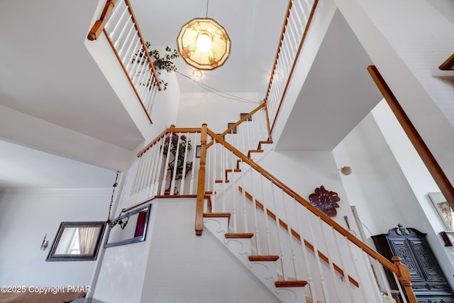 stairs featuring ornamental molding and a high ceiling