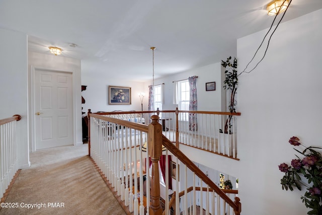 hall with light carpet and an upstairs landing