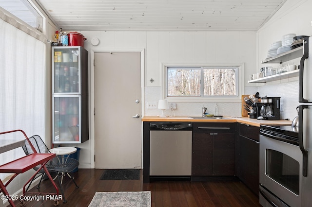 kitchen featuring wooden counters, dark wood-style flooring, stainless steel appliances, and a sink