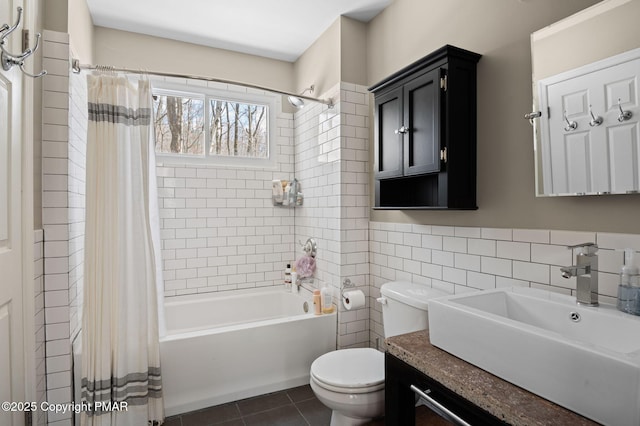 full bathroom with shower / tub combo with curtain, tile walls, toilet, vanity, and tile patterned flooring