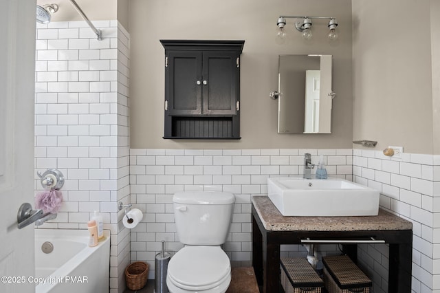 full bath with a wainscoted wall, tile walls, bathtub / shower combination, toilet, and vanity