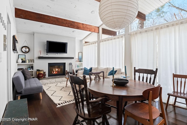 dining space featuring a glass covered fireplace, beamed ceiling, and wood finished floors