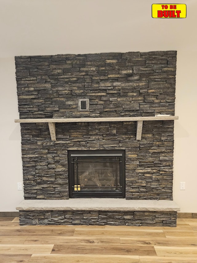 room details featuring a stone fireplace and wood finished floors