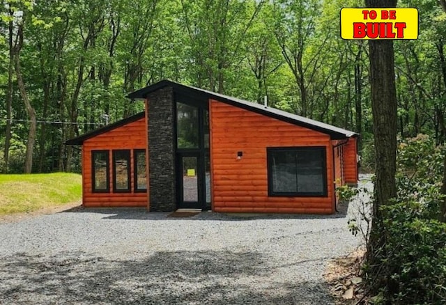 view of front of home featuring log veneer siding and a forest view