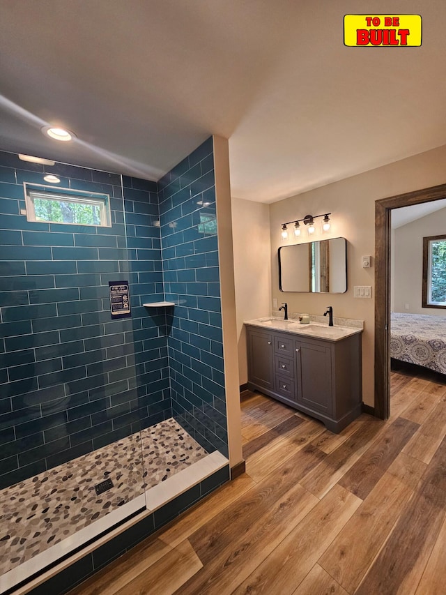 bathroom with tiled shower, wood finished floors, a wealth of natural light, and a sink