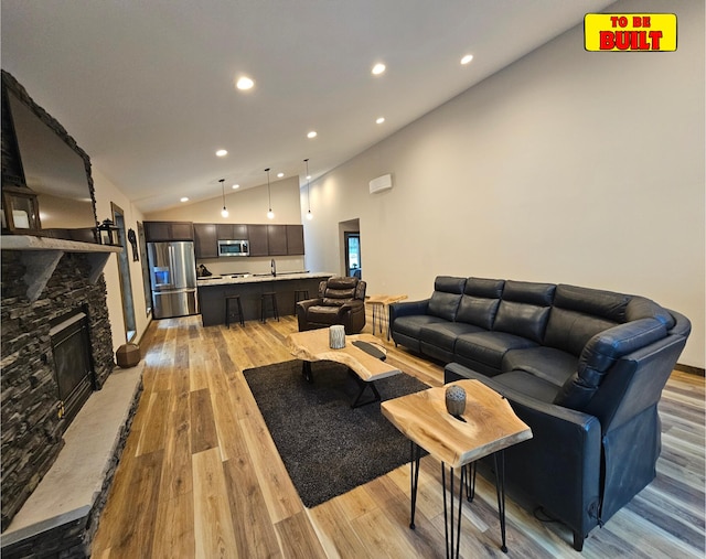 living area featuring recessed lighting, light wood-type flooring, high vaulted ceiling, and a fireplace