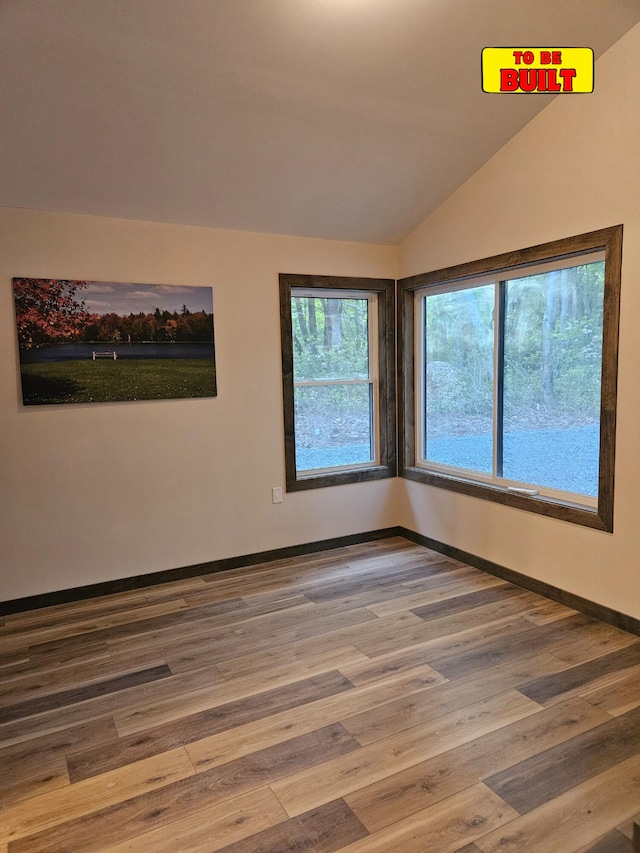 spare room featuring lofted ceiling, wood finished floors, and baseboards