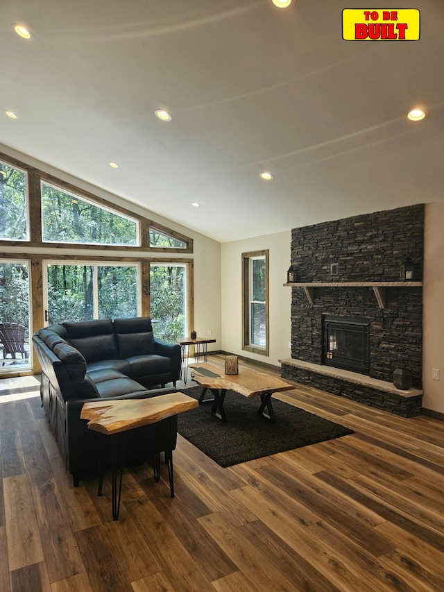 living room featuring recessed lighting, a stone fireplace, wood finished floors, and vaulted ceiling