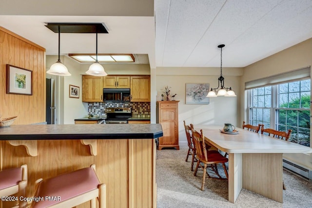 kitchen with hanging light fixtures, tasteful backsplash, appliances with stainless steel finishes, and a kitchen breakfast bar