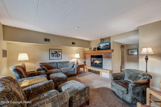 living area with a brick fireplace, carpet, and visible vents