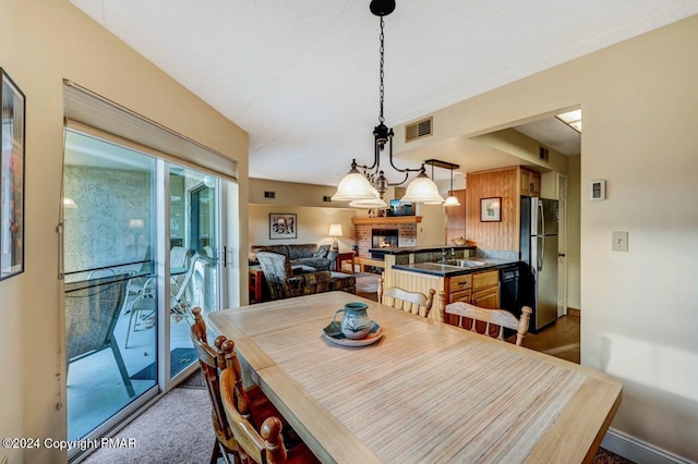 carpeted dining room featuring a brick fireplace, visible vents, and baseboards