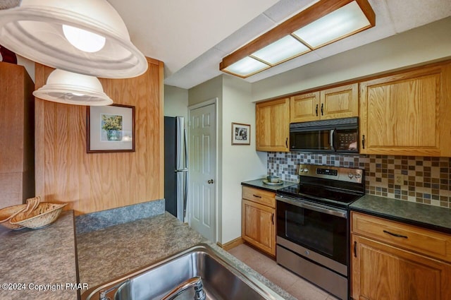 kitchen with dark countertops, light tile patterned floors, appliances with stainless steel finishes, and backsplash