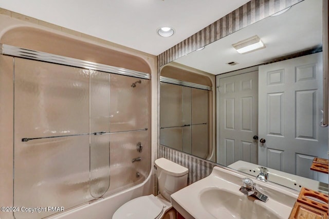 bathroom featuring combined bath / shower with glass door, vanity, and toilet