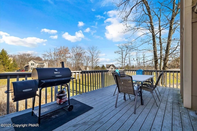 wooden terrace featuring a grill, outdoor dining area, and a yard