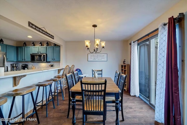 dining area with dark wood-type flooring and a notable chandelier