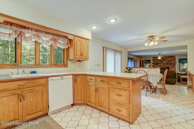 kitchen featuring light countertops, dishwasher, a peninsula, and a sink