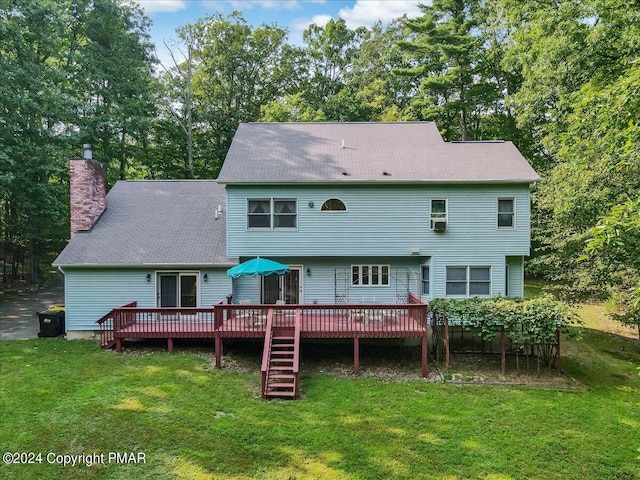 rear view of house featuring a wooden deck, a chimney, and a yard