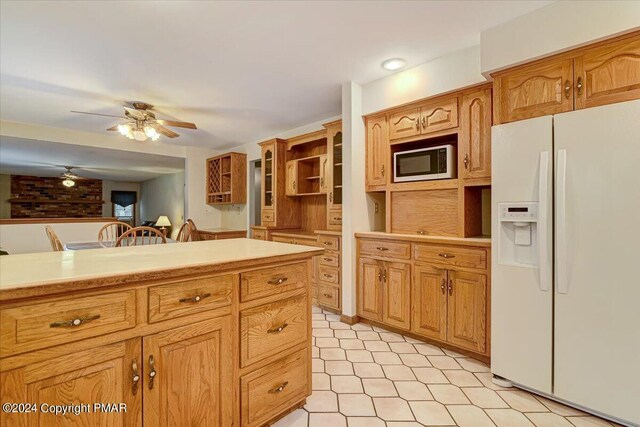 kitchen featuring ceiling fan, brown cabinets, light countertops, white fridge with ice dispenser, and open shelves