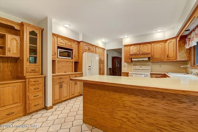 kitchen featuring white appliances, light countertops, a sink, and a peninsula