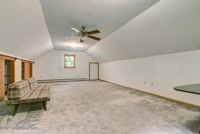 additional living space featuring baseboards, a baseboard radiator, vaulted ceiling, a textured ceiling, and carpet floors