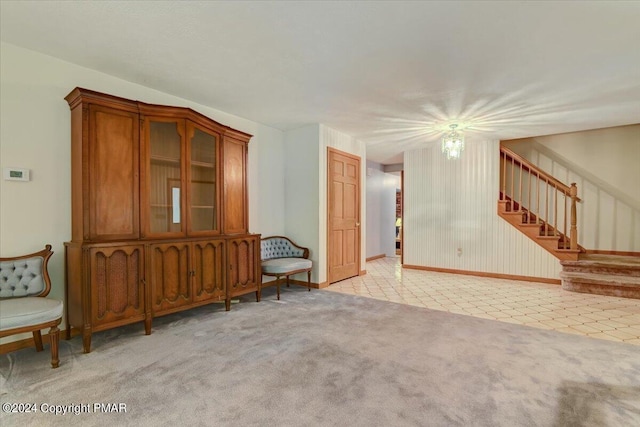 unfurnished living room featuring stairway and light colored carpet