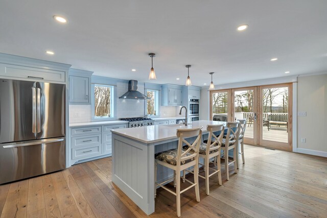 5126 Beattys Cir, Buck Hill Falls, PA 18323 - kitchen with stainless steel appliances, wall chimney range hood, light countertops, a center island with sink, and tasteful backsplash