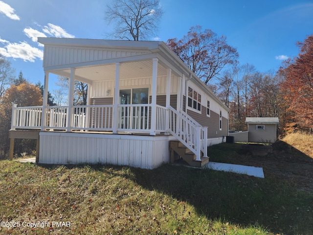 back of house featuring an outbuilding, a porch, a lawn, and a shed