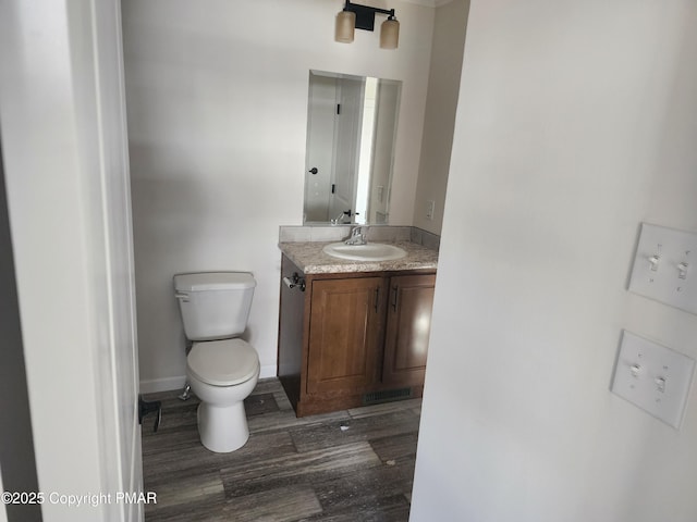 bathroom with vanity, wood finished floors, visible vents, baseboards, and toilet