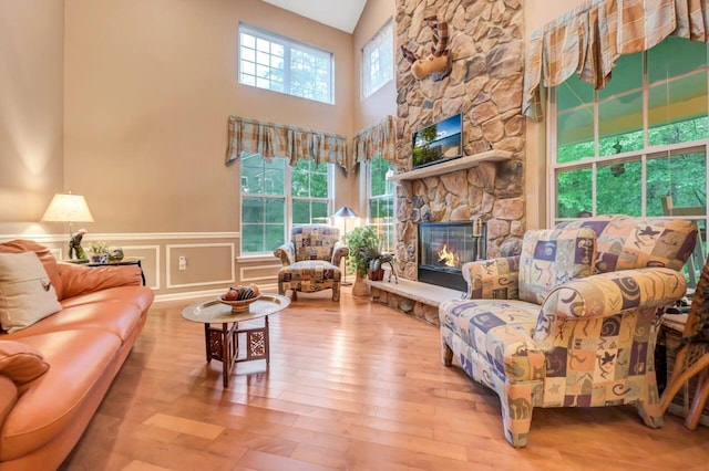 1218 Clymer Ln, Pocono Pines, PA 18350 - living room featuring a fireplace, wood finished floors, a wainscoted wall, and a towering ceiling