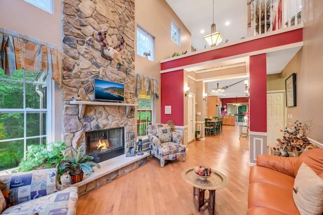 1218 Clymer Ln, Pocono Pines, PA 18350 - living room with wood finished floors, a stone fireplace, a high ceiling, and a wainscoted wall