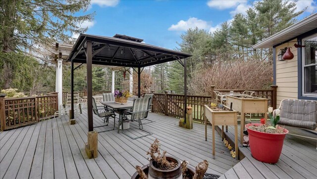 deck with a gazebo, outdoor dining area, and an outdoor fire pit