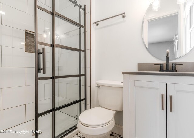 bathroom with a tile shower, toilet, and vanity