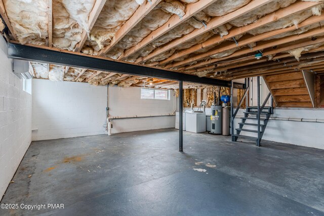 basement featuring washer and clothes dryer, electric water heater, and a wall mounted AC