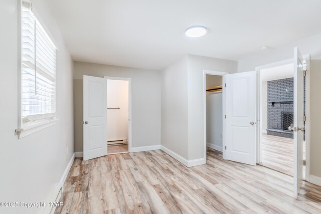 3011 Minqua Cir, Tobyhanna, PA 18466 - unfurnished bedroom with a fireplace, light wood-style flooring, a baseboard heating unit, and baseboards