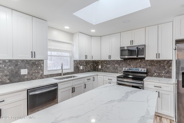 kitchen featuring light stone countertops, white cabinetry, sink, backsplash, and stainless steel appliances