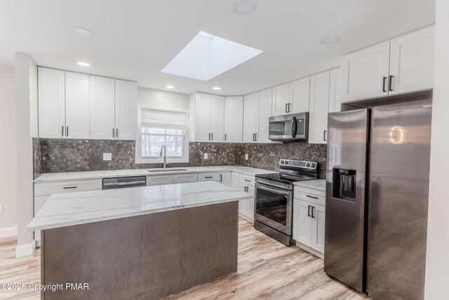 3011 Minqua Cir, Tobyhanna, PA 18466 - kitchen featuring stainless steel appliances, a sink, a skylight, light wood-style flooring, and white cabinetry