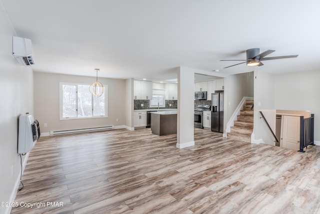 unfurnished living room featuring an AC wall unit, baseboard heating, ceiling fan with notable chandelier, light hardwood / wood-style floors, and heating unit