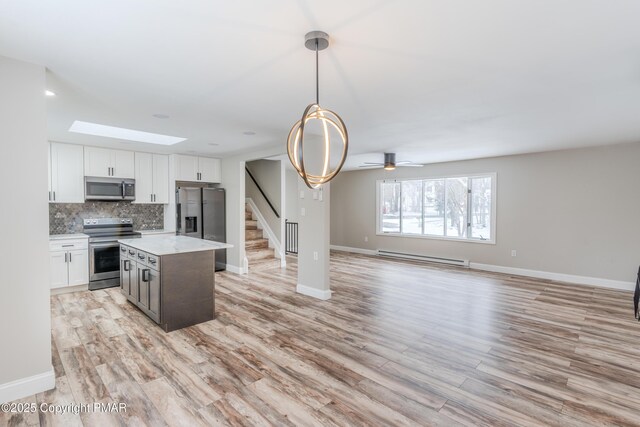 3011 Minqua Cir, Tobyhanna, PA 18466 - kitchen with appliances with stainless steel finishes, open floor plan, backsplash, a skylight, and light wood-style flooring