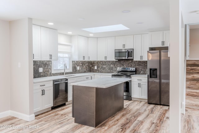 kitchen featuring a kitchen island, white cabinetry, light stone countertops, and appliances with stainless steel finishes