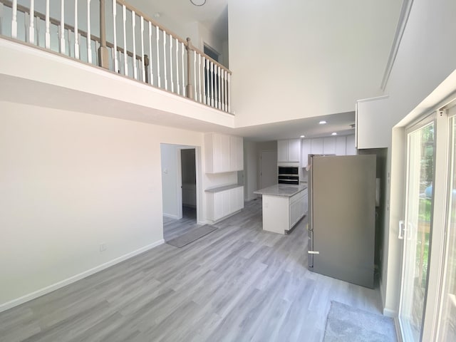 130 Sugar Hill Rd, Saylorsburg, PA 18353 - kitchen featuring a high ceiling, freestanding refrigerator, light wood-style floors, white cabinets, and a kitchen island