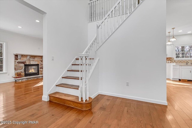 staircase with a high ceiling, sink, hardwood / wood-style floors, and a fireplace