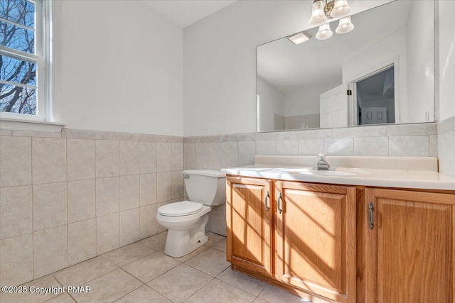 bathroom featuring tile patterned floors, vanity, toilet, and tile walls