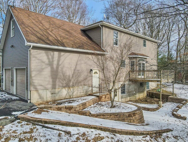 snow covered back of property with a garage