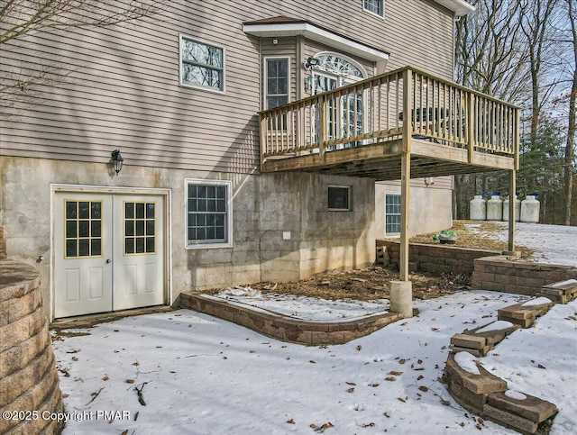 snow covered patio with a wooden deck and french doors