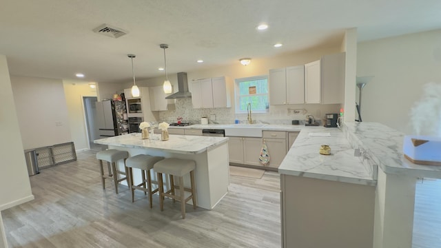 2292 Bismark Rd, Blakeslee, PA 18610 - kitchen featuring wall chimney range hood, a breakfast bar, appliances with stainless steel finishes, a sink, and light wood finished floors