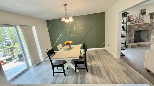 2292 Bismark Rd, Blakeslee, PA 18610 - dining area featuring wood finished floors, a chandelier, a stone fireplace, and baseboards