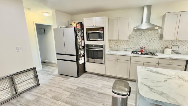 2292 Bismark Rd, Blakeslee, PA 18610 - kitchen with appliances with stainless steel finishes, wall chimney range hood, decorative backsplash, light stone counters, and light wood-style floors