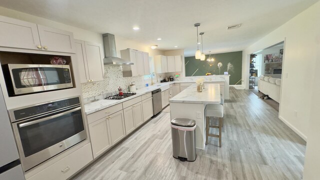 2292 Bismark Rd, Blakeslee, PA 18610 - kitchen with stainless steel appliances, wall chimney exhaust hood, a kitchen breakfast bar, a peninsula, and light wood finished floors