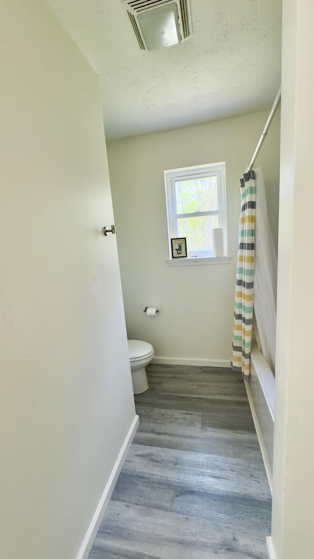 2292 Bismark Rd, Blakeslee, PA 18610 - full bath featuring toilet, baseboards, wood finished floors, shower / bathtub combination with curtain, and a textured ceiling